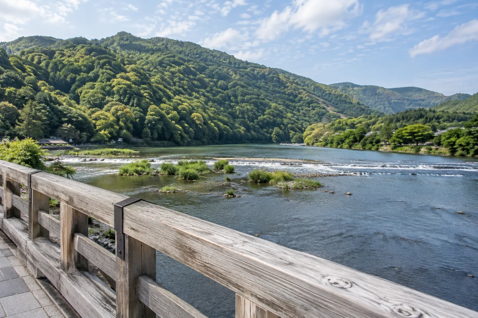 渡月橋の木の欄干越しに眺める桂川と緑の山並み