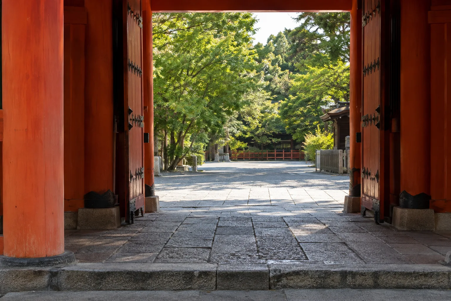 八坂神社の朱色の門の内側から眺める石畳と境内の緑