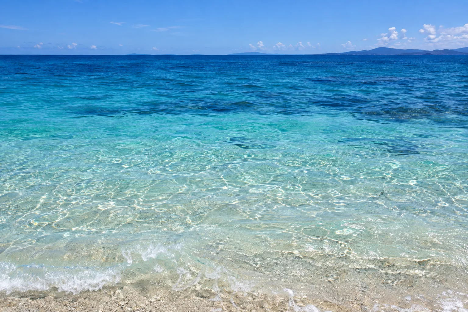 古宇利島の海辺で透明な浅瀬から沖の濃い青へと変わる水面