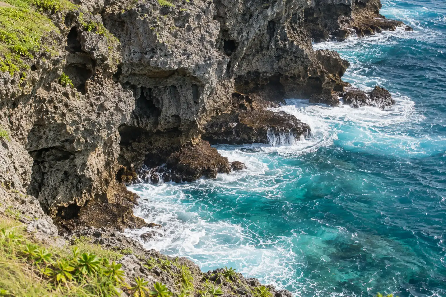 万座毛の陰影のある岩肌と、その下で白く砕ける波